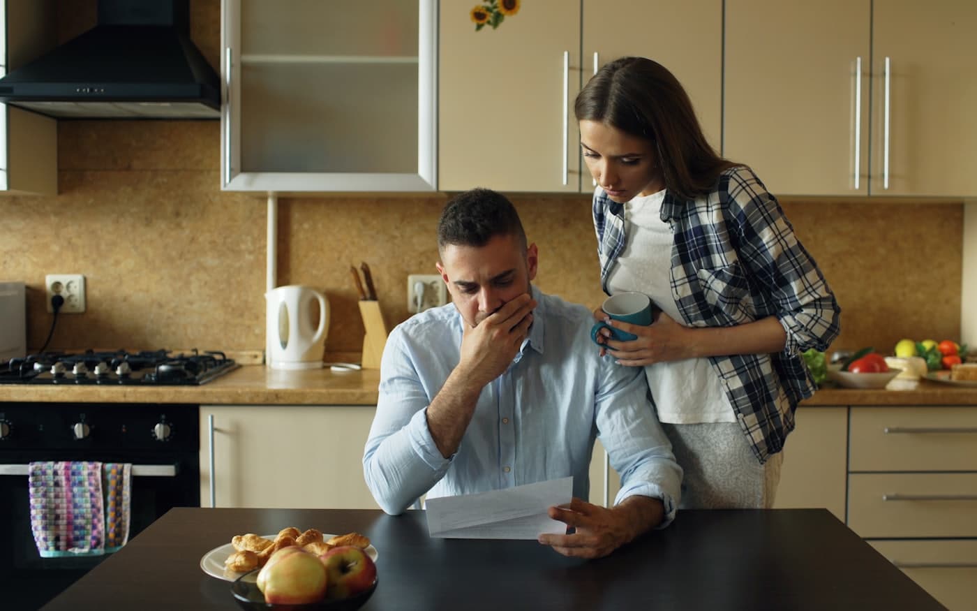 בני זוג בוחנים מכתב מחברת ביטוח במטבח הבית
